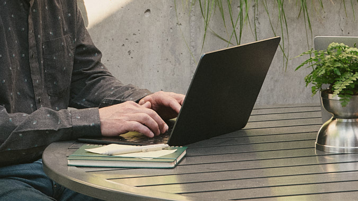 Person working from a laptop on a table outdoors.